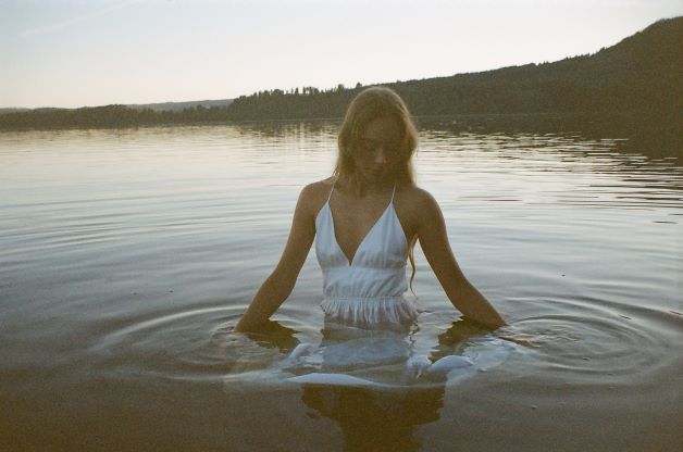 Earthy Vibes bathing in a lake with white flowy dress