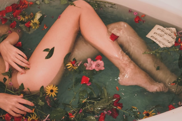 Women laying in a bathtub filled with flowers